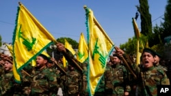 Konbatan Hezbollah yo flote drapo epi kriye slogan pandan fineray yon solda Hezbollah ki rele Bilbl Nemr Rmeiti ki mouri nan yon atak Izrayelyen nan sid Liban, 22 Oktob, 2023. 