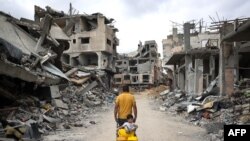 A Palestinian man pulls a boy on a cart on a street lined with destroyed buildings in Khan Yunis in the southern Gaza Strip, May 2, 2024, amid the ongoing conflict between Israel and the militant Hamas movement.