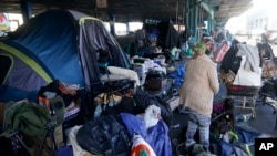 FILE - A woman gathers possessions to take before a homeless encampment was cleaned up in San Francisco, Aug. 29, 2023. 