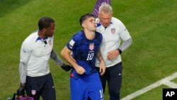 Christian Pulisic, jwe seleksyon nasyonal Etazini kite teren foutbol la ak asistans dokte ekip la apre li make yon gol pou ede Etazini ranpote la viktwa sou Iran nan match Gwoup B li a, 29 Nov. 2022. 