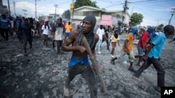 Foto: Yon manifestan pote yon baton bwa pandan yon manifestasyon pou mande Premye Minis Ariel Henry bay demisyon li nan Petion-Ville, Ayiti, 3 Oktob, 2022. 