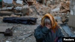 A woman reacts next to the body of her neighbor found under debris of a residential house destroyed by a Russian missile attack in Mykolaiv, Ukraine.