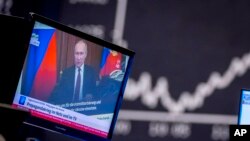 FILE - Russia's President Vladimir Putin appears on a television screen at the stock market in Frankfurt, Germany, Feb. 25, 2022.