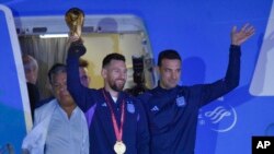 Vedet foutbol Ajantin Lionel Messi kenbe twofe Mondyal Foutbol FIFA a pandan lap desann avyon an ak antrene seleksyon nasyonal la Lionel Scaloni nan Buenos Aires, kapital peyi a, Madi 20 Desanm, 2022. 