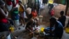 FILE - A woman prepares food at a shelter for families displaced by gang violence in Port-au-Prince, Haiti, Dec. 9, 2021.