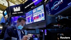 A trader works, as Federal Reserve Chair Jerome Powell is seen delivering remarks on screens