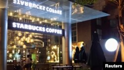 Nhân viên chuẩn bị mở cửa hàng cà phê Starbucks ở TP HCM.