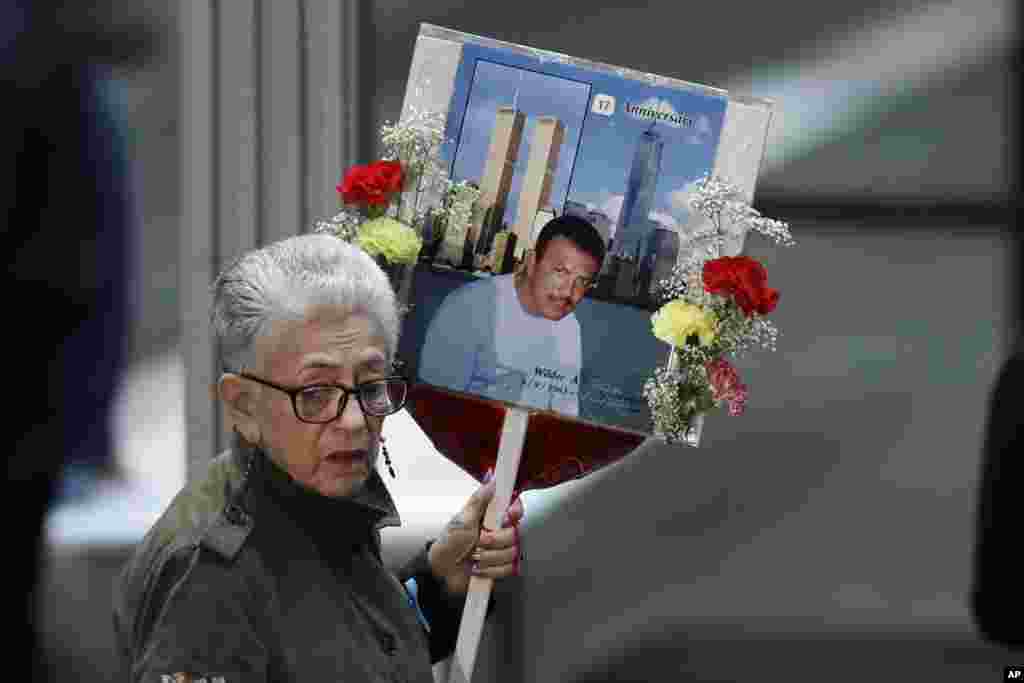 A woman carries a photo of Wilder Gomez who was a bartender at Windows on the World on the 103rd floor of the World Trade Center, during the 17th anniversary of the terrorist attacks on the United States, Sept. 11, 2018, in New York.