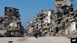 Bé trai Syria cưỡi xe đạp qua khu vực bị tàn phá nặng nề ở thành phố cổ Homs, Syria, ngày 26/2/2016.