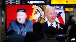 Commuters watch a TV showing a file image of North Korean leader Kim Jong Un and U.S. President Joe Biden during a news program at the Suseo Railway Station in Seoul, South Korea, Friday. March 26, 2021. 