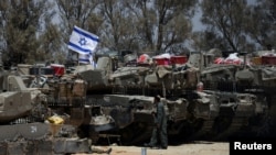 An Israeli soldier walks near military vehicles, amid the ongoing conflict between Israel and the Palestinian Islamist group Hamas, near Israel's border with Gaza in southern Israel