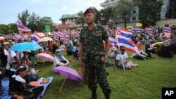 Một binh sĩ Thái Lan đứng cạnh những người biểu tình chống chính phủ trong khuôn viên Bộ tư lệnh Quân đội Hoàng gia Thái Lan ở Bangkok, Thái Lan, 29/11/13