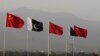 People sit on top of a bus as they go past flags of Pakistan and China that are displayed along a road, ahead of Chinese Premier Li Keqiang's visit to Islamabad May 21, 2013. Li will arrive on two-day official to Pakistan on May 22. REUTERS/Faisal Mahmood