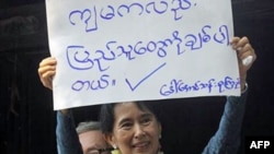 Bà Suu Kyi giơ cao tấm bảng "Tôi cũng yêu mọi người" cho những người ủng hộ bà tại trụ sở của NLD ở Yangon, Miến Điện, 14/11/2010