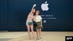 Khách hàng chụp ảnh tự sướng bên ngoài một cửa hàng Apple ở Bắc Kinh hôm 16/8.