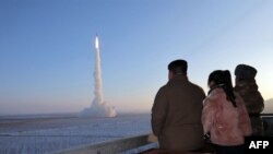 (FILES) This undated picture released by North Korea's official Korean Central News Agency (KCNA) on December 19, 2023 shows North Korean leader Kim Jong Un (L) and his daughter watching the test launch of a Hwasongpho-18 intercontinental ballistic missil