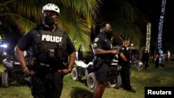 Police officers stand guard as revelers enjoy spring break festivities in Miami Beach, Florida, March 22, 2021.