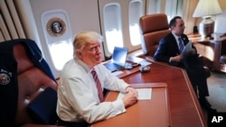 President Donald Trump, with his Chief of Staff Reince Priebus, sits at his desk on Air Force One upon their arrival at Andrews Air Force Base, Jan. 26, 2017.