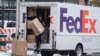 Foto Achiv: Yon anplwaye FedEx pote yon koli, 17 Nov. 2022. 