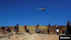 Máy bay trực thăng Mỹ tuần tra trong khi di dân leo hàng rào ngăn cách Mexico và Mỹ tại Tijuana, Mexico ngày 25/11/2018.