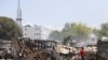 People walk past remains of vehicles after they were set on fire by gangs, in Port-au-Prince