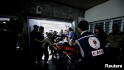 FILE PHOTO: People are assisted at Shifa Hospital after hundreds of Palestinians were killed in a blast at Al-Ahli hospital in Gaza that Israeli and Palestinian officials blamed on each other