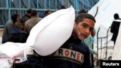 FILE PHOTO: Palestinians gather to receive bags of flour distributed by UNRWA, in Rafah