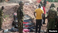 Kenyan military personnel stand near bodies lined up on the ground at a quarry site where attackers killed at least 36 workers in a village in Korome, outside the border town of Mandera, Dec. 2, 2014.