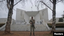 A security official stands guard outside the Supreme Court in Pakistan where PM Gilani was scheduled...