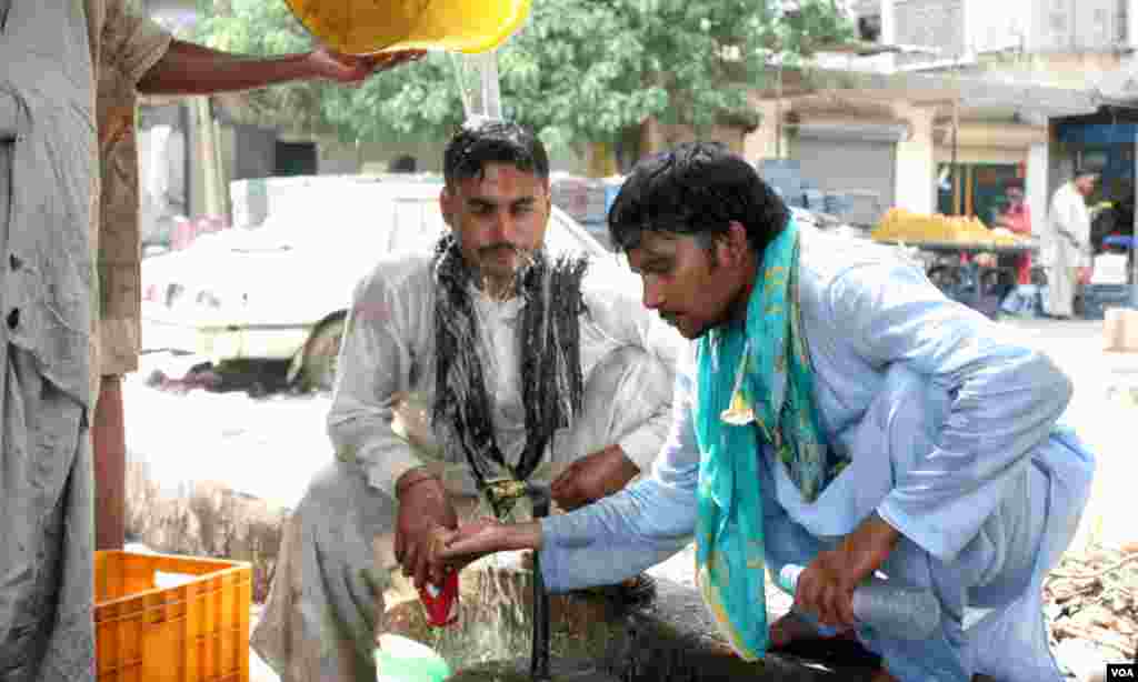 گرمی سے بچنے کے لئے سروں پر پانی ڈالتے ہوئے راہ گیر