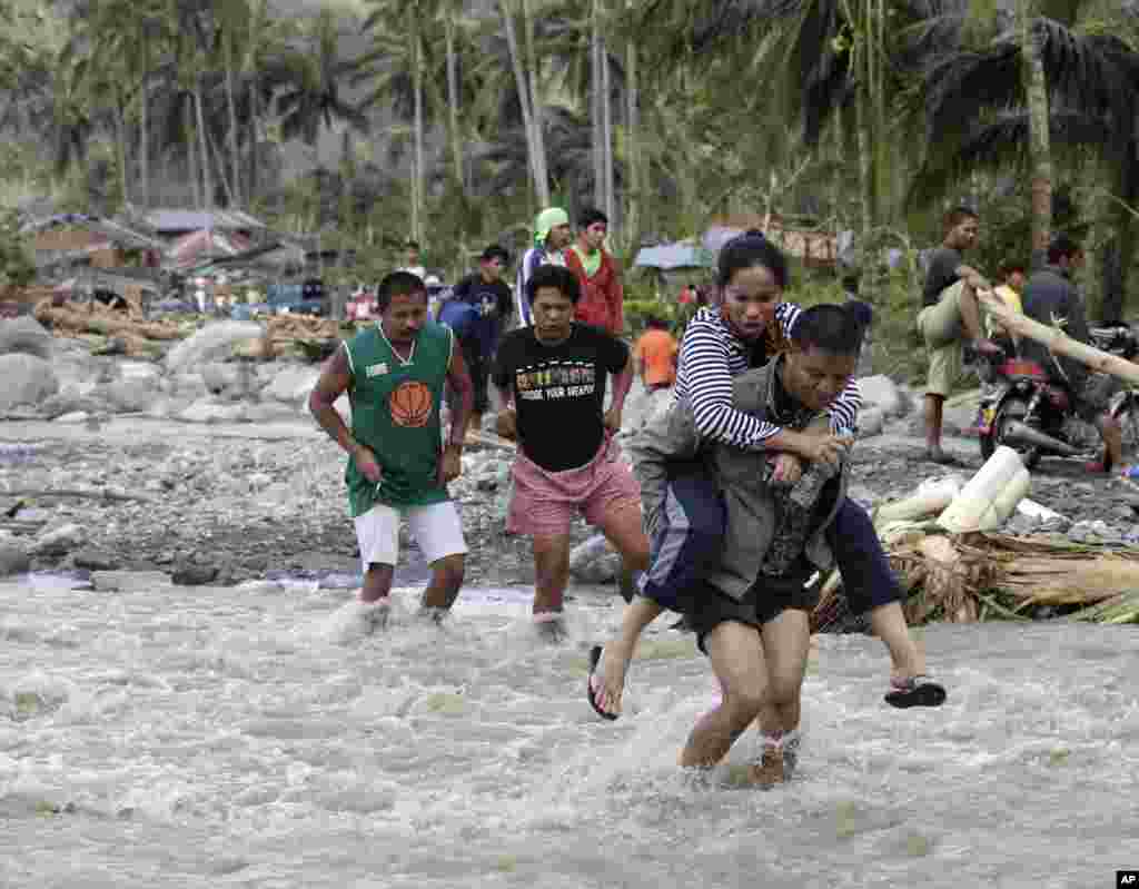 Dân trong làng Andap, tỉnh Compostela Valley tìm cách băng ngang một khu vực gặp lũ quét.