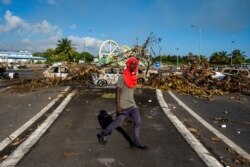 Yon Guadeloupeyen gade kamera a pandan lap pase devan yon barikad ki bloke otowout N1 nan Petit-Bourg, Guadeloupe, 23 Nov. 2021.