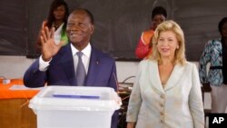 Tổng thống Bờ Biển Ngà Alassane Ouattara (trái) sau khi bỏ phiếu cùng vợ, bà Dominique Ouattara (phải) tại Abidjan, Chủ nhật ngày 25/10/2015.