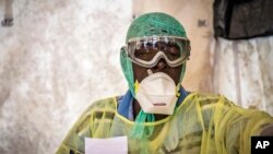 Một nhân viên y tế kiểm tra Ebola cho bệnh nhân bên trong một căn lều khám bệnh ở Bệnh viện Chính phủ Kenema ở Sierra Leone. 