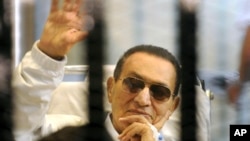 Cựu Tổng thống Ai Cập Hosni Mubarak vẫy chào người ủng hộ sau song sắt của phiên tòa tại Cairo, ngày 13/4/2013.