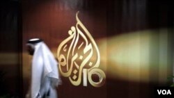 Tư liệu - Một nhân viên người Qatar của kênh tin tức Al-Jazeera tiếng Ả-rập đi ngang qua logo của Al-Jazeera ở Doha, Qatar.