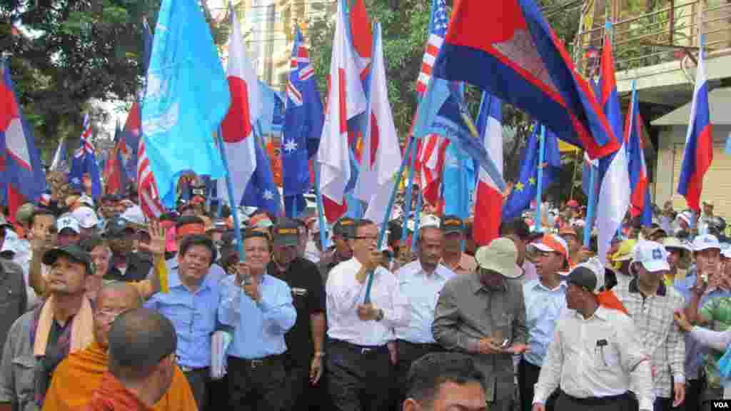 Lãnh đạo đối lập Sam Rainsy và Kem Sokha cầm cờ LHQ, Campuchia và cờ của đảng Cứu Quốc trên đường tuần hành đến văn phòng LHQ tại Phnom Penh, ngày 23/10/2013. 