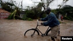 Một người đàn ông đẩy xe đạp qua khu vực ngập nước sau khi cơn bão Matthew đi qua Haiti, ngày 4 tháng 10 năm 2016. 