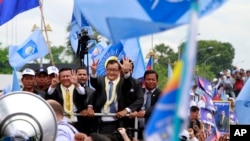 Ông Sam Rainsy (giữa), chủ tịch Đảng Cứu Quốc Campuchia chào các ủng hộ viên khi về đến sân bay Phnom Penh, 19/7/13