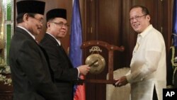 Tổng thống Philippines Benigno Aquino III (phải) nhận chiếc cồng của Chủ tịch Mặt trận Giải phóng Hồi giáo Moro trước khi ký một thỏa thuận khung lịch sử vào năm 2012