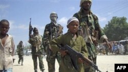 Một bé trai dẫn đầu các thành viên al Shabab trong một cuộc diễn tập quân sự ở ngoại ô Mogadishu, Somalia