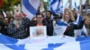 A participant displays a photo of a family held hostage by Palestinian militants in the Gaza Strip, during a rally in front of the Brandenburg Gate in central Berlin on October 6, 2024, ahead of the one-year anniversary of the October 7 attack on Israel b