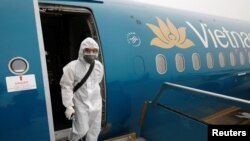 Nhân viên y tế phun thuốc khử trùng máy bay của Vietnam Airlines.